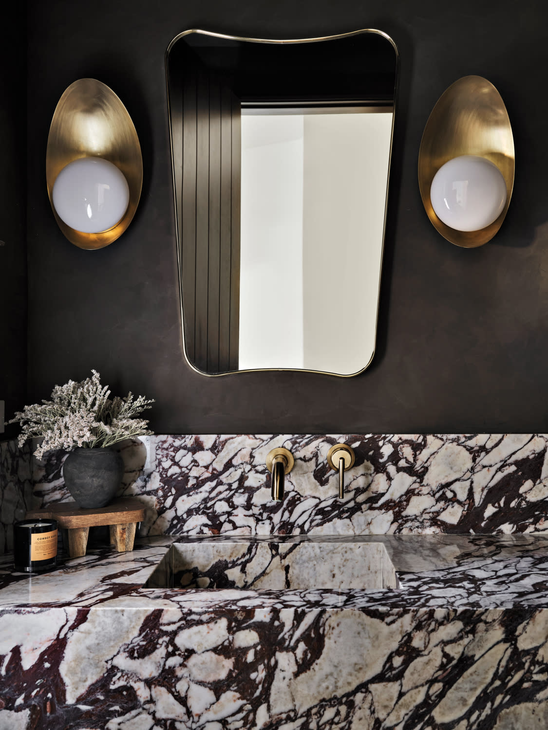 powder bathroom vanity vignette with purple veined marble countertops and sink with brass hardware