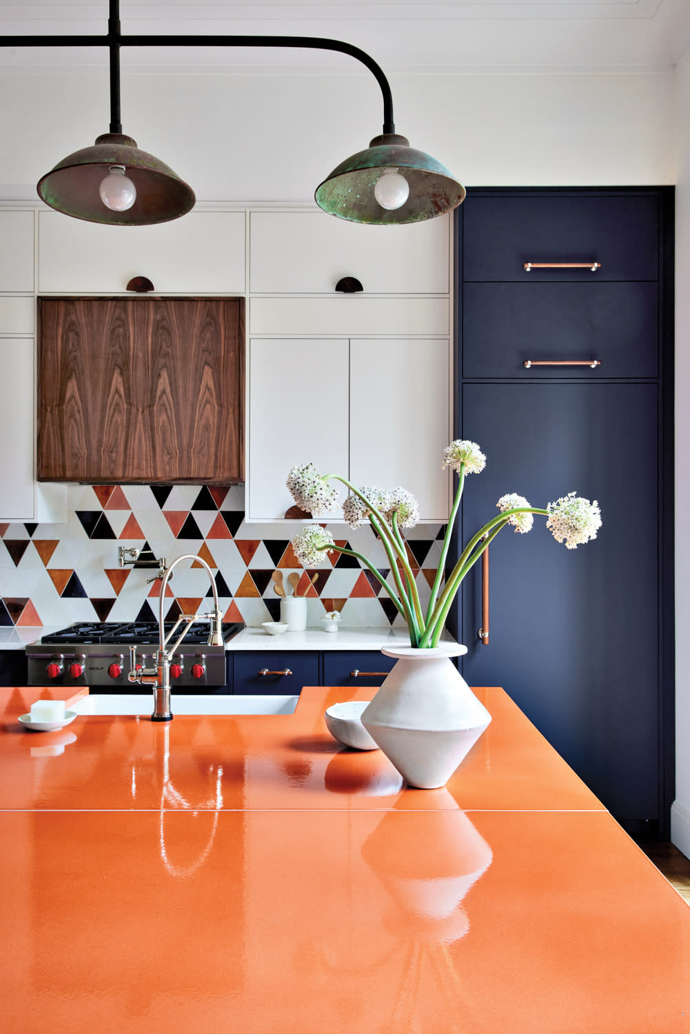 a kitchen with an orange countertop and a mosaic triangle tile backsplash