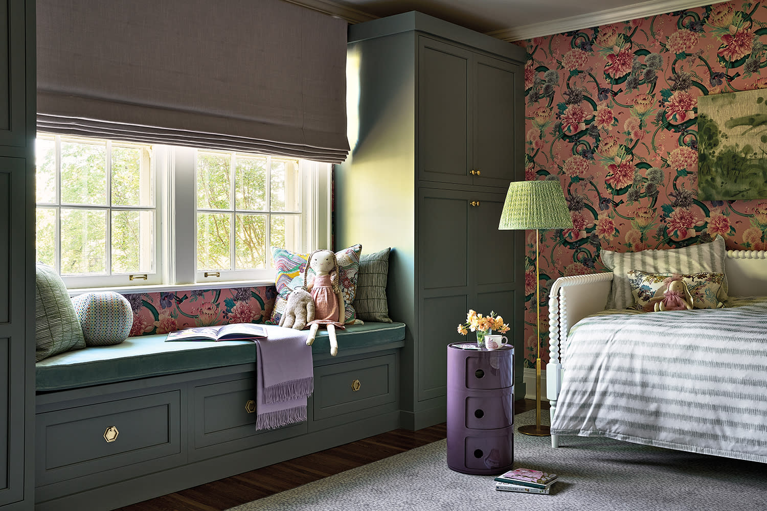girly bedroom with a floral wallpaper, green window seat and matching green storage