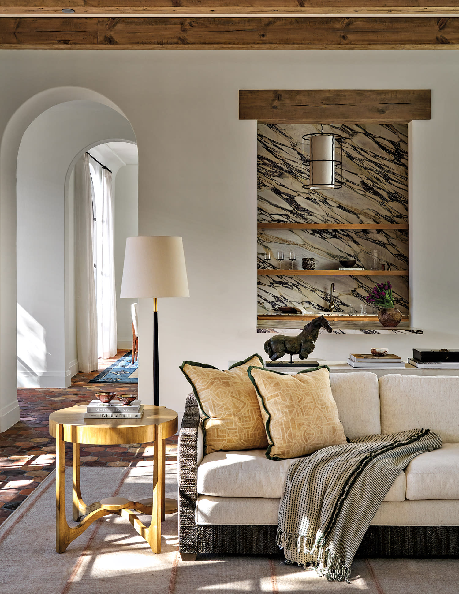 living room vignette with an arched doorway and a marbled niche above a sofa